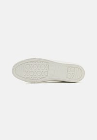 Talpa de sneaker alb cu o suprafață din cauciuc texturat, având un model hexagonal și un design de tracțiune în forma de romb. Finisaj neted.