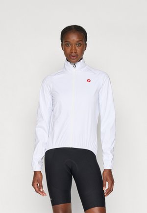 Weiße, leichte Fahrradjacke mit hohem Kragen, Reißverschluss, dehnbaren Bündchen und rotem Logo auf der linken Brust. Tragen mit schwarzen Fahrradhosen.