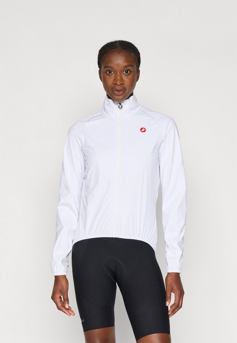 Weiße, leichte Fahrradjacke mit hohem Kragen, Reißverschluss, dehnbaren Bündchen und rotem Logo auf der linken Brust. Tragen mit schwarzen Fahrradhosen.