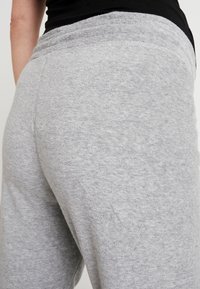 Grå fleecebyxor med elastisk midja. Tyget är mjukt med en slät yta och ett lätt melerat mönster.