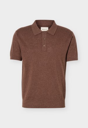 Tricou polo maro din tricot cu mâneci scurte, trei nasturi și guler și tiv striați, prezentat pe un fundal deschis, simplu.