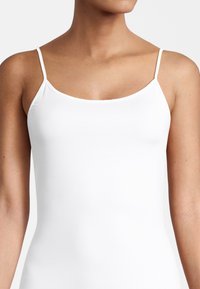 White camisole with thin straps, featuring a smooth, stretchy fabric that conforms to the body and has no visible patterns or embellishments.