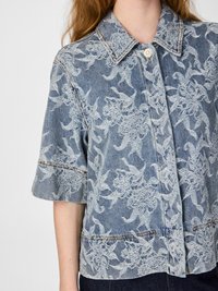 Jeansjacka i ljusblått tyg med broderade blommönster, krage, korta ärmar och knappstängning.