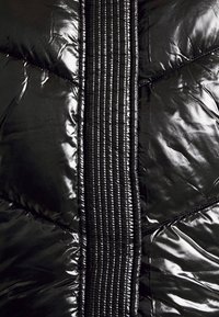 Chaqueta de plumas negra con un acabado brillante, diseño acolchado, acentos de canalé vertical y una textura elegante con costuras contrastantes.