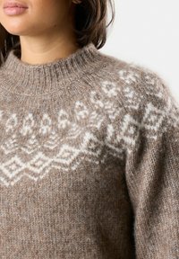 Pull brown in maglia con collo alto, caratterizzato da motivi geometrici bianchi lungo il collo e le spalle, realizzato in materiale morbido e testurizzato.