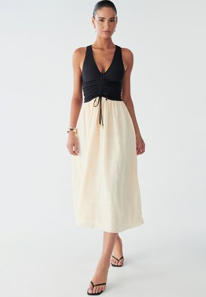 Maxi sukienka z teksturowaną czarną górą i zwiewną kremową spódnicą z poziomym wzorem. Regulowany sznurek w talii.