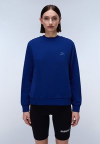 Blauwe sweatshirt van een katoenmix, met een ronde hals, geribbelde mouwen en een klein logo op de borst. Gecombineerd met zwarte shorts.