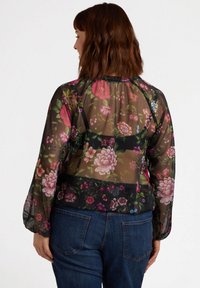 Bluză neagră transparentă cu un model floral în nuanțe de roz și verde. Mâneci lungi, decolteu plisat și croială lejeră. Purtați cu blugi blue.