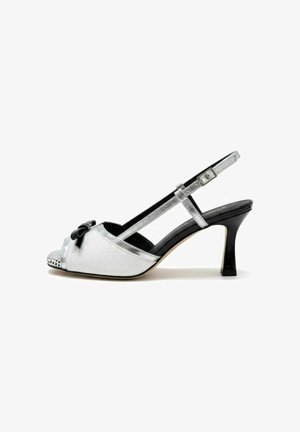 Tacco slingback bianco con punta aperta, fiocco nero, cinturini argento, punta testurizzata e tacco nero a goccia di media altezza.