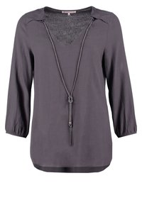 Graue Langarmbluse mit V-Ausschnitt, die einen strukturierten Kragen und eine dekorative Kordel mit Quasten-Detail aufweist. Glatte Stoffoberfläche.