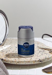 Nivea Men Anti-Age Hyaluron cream in a cylindrical grey container with a blue cap. Features a textured finish and blue label with text.