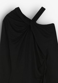 Haut noir drapé en tissu doux. Présente un design tordu à l'épaule et un ourlet asymétrique avec des détails froncés d'un côté.