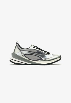 Baskets basses argentées et grises avec des lacets noirs, des panneaux en mesh et une semelle épaisse blanche et noire, vues de côté sur fond blanc.