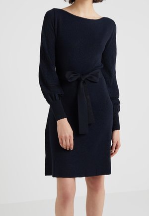 Navy sweater dress with long, textured puff sleeves, a round neckline, and a tied waist accent. Soft fabric with a slight shimmer.