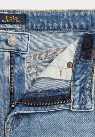 Φωτεινό μπλε τζιν παντελόνι από denim με φερμουάρ και χρυσά εξαρτήματα, ετικέτα σε ναυτικό μπλε με την επιγραφή "Polo Ralph Lauren" και πορτοκαλί ραφές.