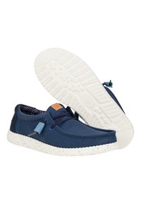 Baskets en toile marine avec des semelles blanches à pois, design à lacets et une étiquette en cuir. L'intérieur présente un motif rayé.