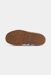 Rubber shoe sole with a hexagonal tread pattern, featuring a circular design at the heel and a logo engraved on the side.