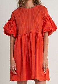 Vestido rojo con un cuerpo de textura acanalada y mangas abullonadas, que presenta una falda acampanada y un acabado suave. Diseño casual y ligero.