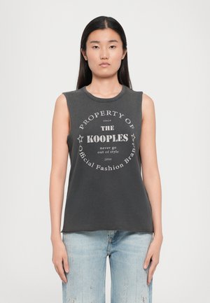 T-shirt sans manches gris foncé en mélange de coton, avec un graphique circulaire contenant du texte et des étoiles, associé à un jean en denim bleu clair.