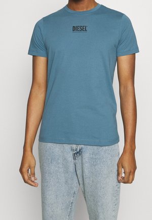 Camiseta de algodón de manga corta en color azul con cuello redondo y un logo impreso en negro de "DIESEL" en el pecho. Corte casual.