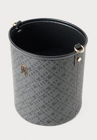 Grijze cilindervormige stoffen tas met zwarte binnenkant, witte stiksels, gouden hardware en subtiel geometrisch patroon, open aan de bovenkant.