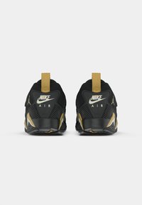 Mustad musta Nike Air spordijalanõud, mis sisaldavad musta võrkkangast pealmist, kuldseid detaile ja tekstureeritud tallat. Kergeks selga panemiseks on lisatud kuldne kannaosa.