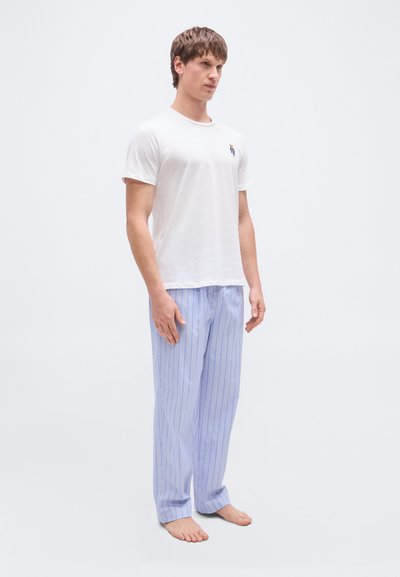 Άσπρο βαμβακερό μπλουζάκι με μικρό κεντητό σχέδιο, σε συνδυασμό με ανοιχτό μπλε ριγέ πιτζάμα παντελόνι από απαλό ύφασμα.