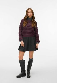 Violet tekstūruotas megztinis su raštuotu apvadu, pilka platėjančia sijoną, pilkas iki kelių kojinių ir juodos iki kelių išgręžtos botai. Paprastas ir daugiasluoksnis dizainas.