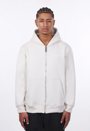Lys grå zip-up hoodie lavet af blødt stof med en frontlomme, ribbede manchetter og broderet logo på venstre bryst.