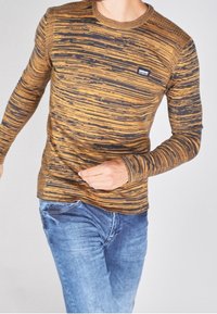 Koszula z długim rękawem w brązowo-czarny paski, wykonana z miękkiej tkaniny. Posiada okrągły dekolt i małe logo marki na piersi.
