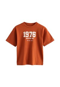 Orange bomulds t-shirt med rund halsudskæring, korte ærmer og et grafisk print med "1976" og "BEDFORD AVE" i hvid.