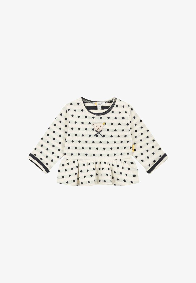 Long-sleeve top in cream with black polka dots, featuring a frilled hem and embroidered bear design on the front, with contrasting cuffs.