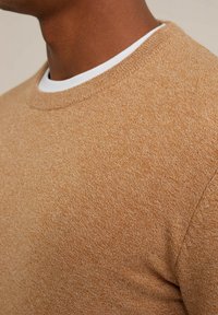 Brun, texturerad tröja med rundad halsringning, som har ett subtilt melerat mönster och ett mjukt, vävt utseende.