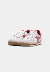 White and red sneakers with a suede upper, mesh panels, and rubber outsole. Features white laces and a red accent logo.
