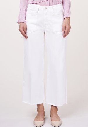 White wide-leg denim pants with a raw hem, featuring front pockets and a classic button closure. Worn with beige pointed-toe shoes.