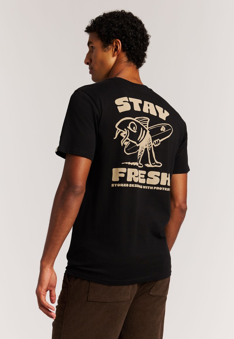 Camiseta negra de algodón con un gran gráfico color crema en la espalda que muestra un pez y una tabla de surf con el texto "STAY FRESH".