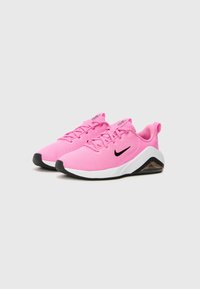 Baskets de sport roses avec tige en mesh, design à lacets, logo swoosh noir et semelle intermédiaire blanche dotée d'une unité de coussin d'air visible.