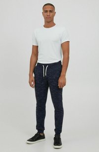 White crew-neck t-shirt and navy joggers with a speckled texture, featuring a drawstring waist and cuffed ankles, paired with black sneakers.