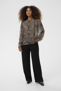 Blusa trasparente con stampa leopardata e maniche lunghe, dettagli con bottoni, abbinata a pantaloni neri a gamba larga e ballerine nere a punta.