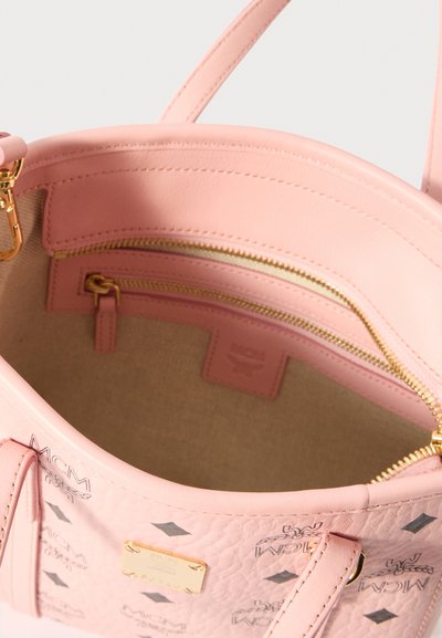Różowa skórzana torba z teksturowaną powierzchnią, wewnętrznymi kieszeniami na zamek błyskawiczny, złotymi akcentami i podszyciem z tkaniny. Logo MCM wyeksponowane w widocznym miejscu.