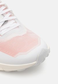 Scarpa da corsa con una tomaia in mesh bianco e rosa morbido, arricchita da dettagli testurizzati. La suola in gomma presenta un motivo per garantire aderenza e stabilità.