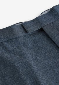 Dark blue denim fabric with a textured surface. Features a folded waistband and stitching details. Smooth finish and no visible patterns.