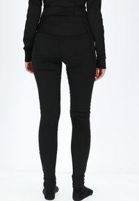 Sorte ribbede leggings, tætsiddende design, høj talje, glat tekstur, med en tætsiddende pasform fra talje til ankel. Ingen bemærkelsesværdige mønstre eller accenter.