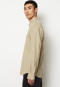 Beige kariertes Hemd mit Button-Down-Kragen, langen Ärmeln mit Knopfverschlüssen und einer lockeren Passform.