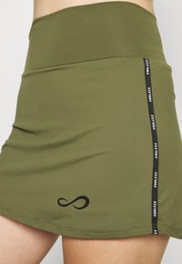 Kevyt vihreä hame, jonka vyötärö on istuva ja korkea. Hameessa on musta sivu-urheiluraita, joka on merkitty sanoin "ENDLESS", sekä hillitty musta äärettömyyslogo.