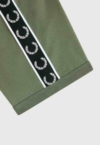 Manchon en tissu vert avec une bande verticale noire bordée de blanc, comportant des symboles répétés de couronnes de laurier blanches.