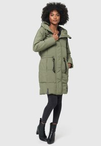 Olijfgroene gewatteerde jas met een capuchon, voorzakken, een trekkoord in de taille en zwarte accenten. Draag het over zwarte leggings en enkellaarsjes.