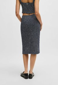 Donkerblauw textured twee-delig outfit met een cropped top en een pencil skirt. Bevat een rits aan de achterkant en een aansluitend ontwerp. Zwarte schoenen maken de look compleet.