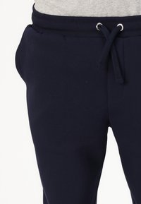 Navy blauwe joggerbroeken gemaakt van zachte katoen, met een elastische tailleband en trekkoord, zijzakken en een gladde textuur.