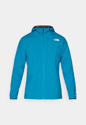 Veste imperméable en bleu vif, avec une capuche bordée de noir, une fermeture éclair complète et des poignets élastiques. Logo affiché en haut à gauche sur le devant.